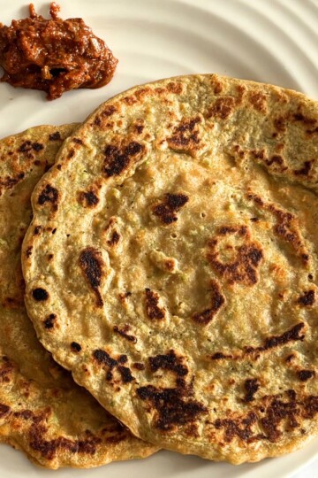 2 Red Lentil Chila served in a cream plate along with red garlic chutney.