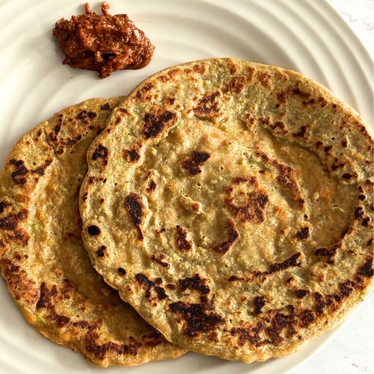 2 Red Lentil Chila served in a cream plate along with red garlic chutney.