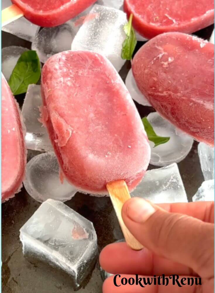 Watermelon Pomegranate Popsicles arranged on Ice cubes with Ice tray.