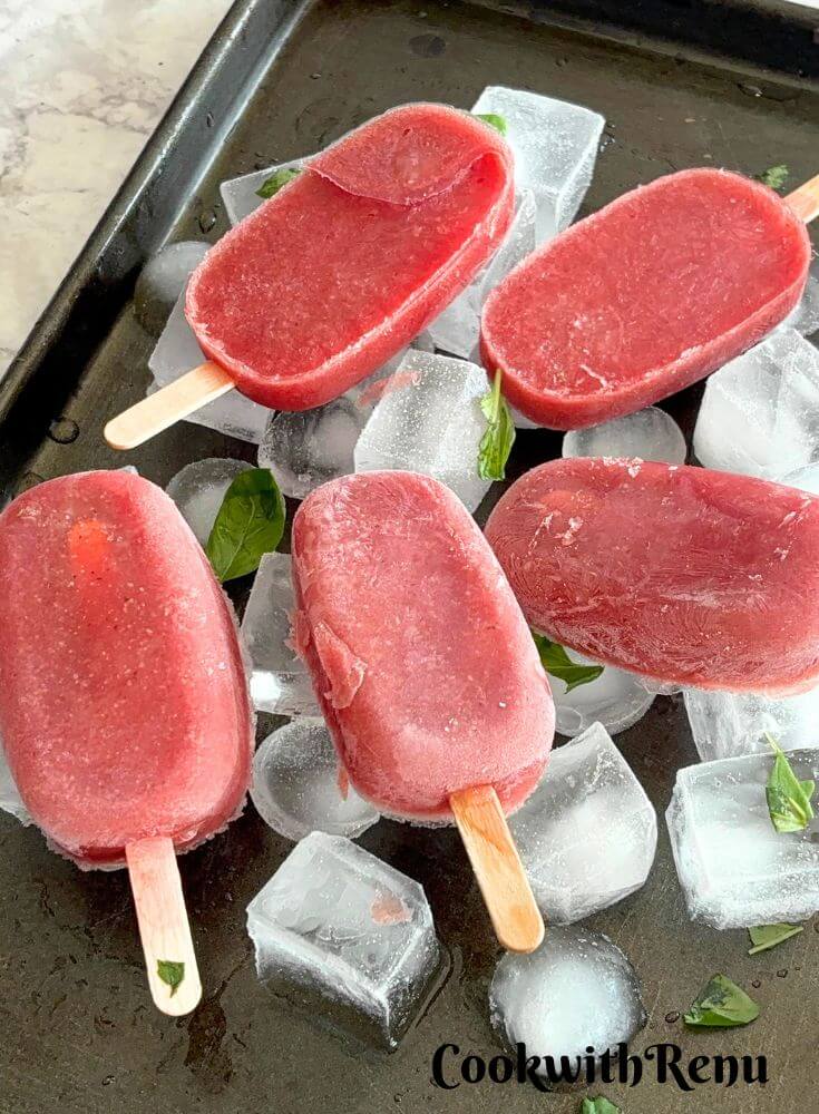 Watermelon Pomegranate Popsicles arranged on Ice cubes with Ice tray.