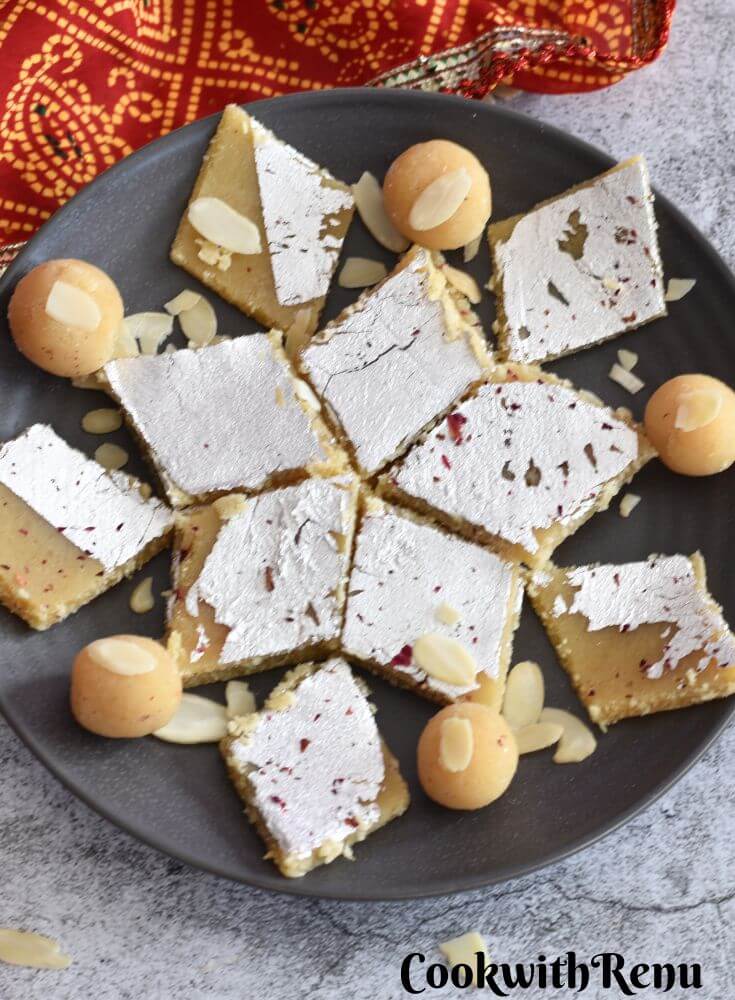 Almond Flour Burfi and Ladoo are arranged on a grey plate, with a red dupatta in the background.