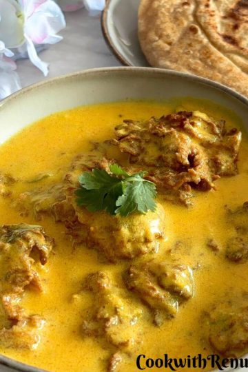 Close-up look of No Onion No Garlic No Tomato Dudhi Kofta Curry served in a bowl, with some parathas in the side.