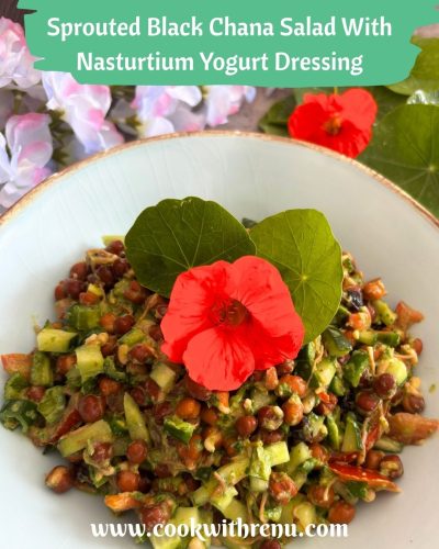 Sprouted Black Chana Salad With Nasturtium Yogurt Dressing, served in a sky-coloured bowl with golden lining and a garnish of nasturtium leaves and flowers. Seen in the background are some nasturtium leaves and flowers.