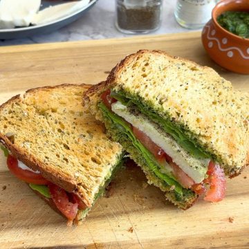 Basil Chutney Caprese Sandwich cut in half and served on a cream cheese board.