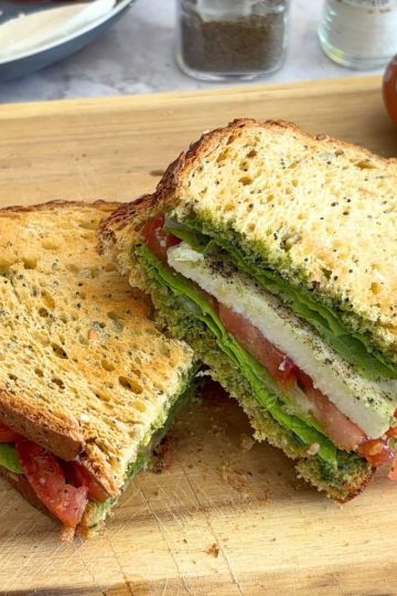 Basil Chutney Caprese Sandwich cut in half and served on a cream cheese board.