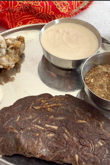 Close-up of a Navratri vrat thali with kuttu aloo cheela, farali arbi, yogurt-based sides, and kuttu panjiri.